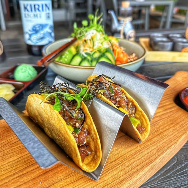 Two Chronic Sushi tacos with seaweed and cilantro, a poke bowl, and a Kirin beer bottle.